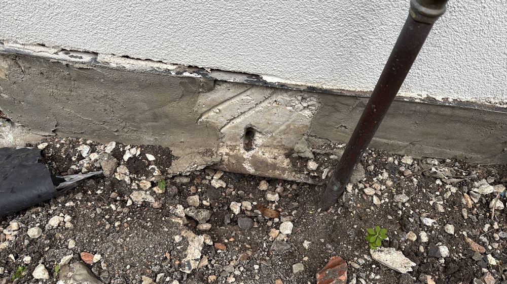 Rough concrete patch repair with reinforcement still exposed, found during a defect investigation in Herne Hill